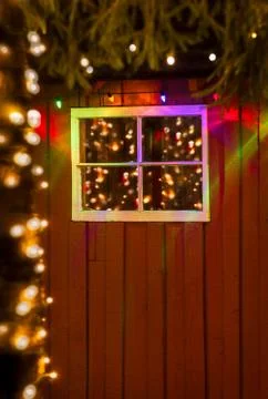 Christmas lights reflected in old window of rustic red painted w Stock Photos