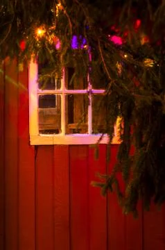 Christmas lights reflected in old window of rustic red painted w Stock Photos