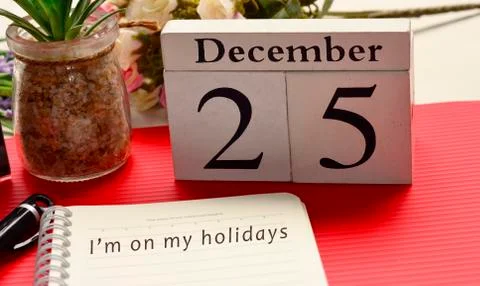 Christmas message written on notepad with white cube and red background Stock Photos