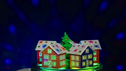 Christmas in motion green tree surrounded by houses rotates on blue background Stock Footage 297746237
