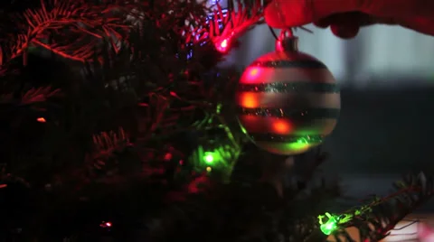 Christmas ornament gets put on tree branch with lights Stock Footage 33741508