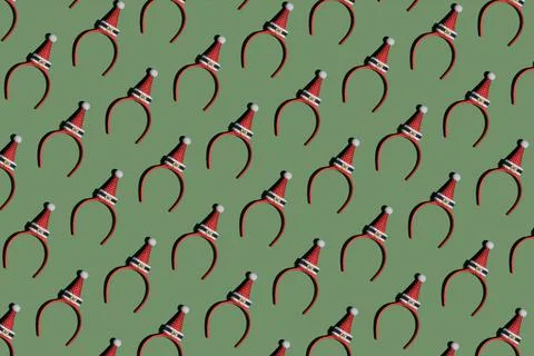 Christmas pattern of funny headbands with red Santa hats on green background Stock Photos