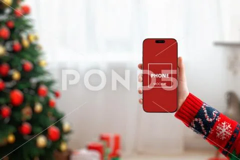 Christmas phone mockup in front of decorated tree Template PSD