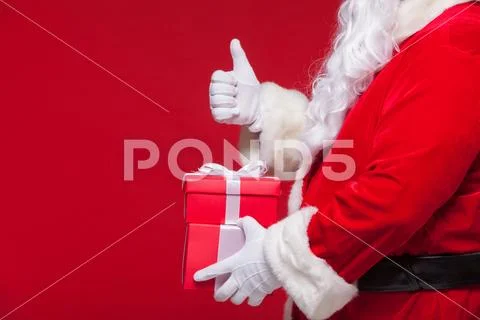 Christmas Photo of Santa Claus gloved hand with red giftbox. thumb up Stock Photos