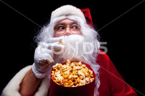 Christmas. Photo of Santa Claus gloved hand With a red bucket with popcorn, on a Stock Photos