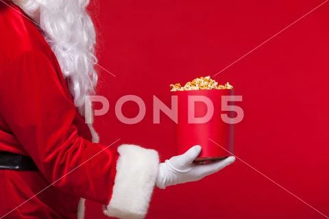 Christmas. Photo of Santa Claus gloved hand With a red bucket with popcorn, on a Stock Photos