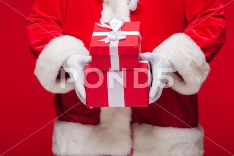 Christmas Photo of Santa Claus gloved hand with red giftbox Stock Photos