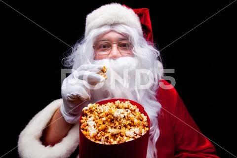 Christmas. Photo of Santa Claus gloved hand With a red bucket with popcorn, on a Stock Photos