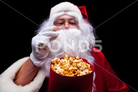 Christmas. Photo of Santa Claus gloved hand With a red bucket with popcorn, on a Stock Photos