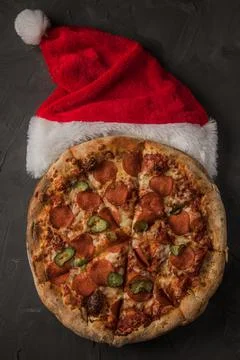Christmas pizza with a santa hat, on a black stone table. Stock Photos