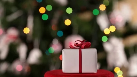 Christmas present in front of decorated xmas tree Видео 81389461