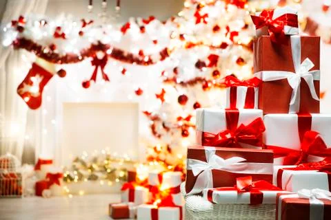 Christmas Present Gift Boxes over Defocused Xmas Tree in Home Room Background Stock Photos