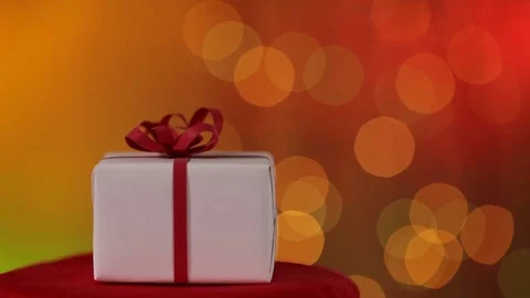 Christmas present spinning and sliding in front of warm and blurry xmas lights Video stock 80948907