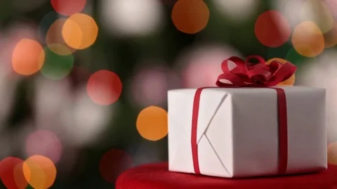 Christmas present spinning in front of blurry xmas lights Stock Footage 81389535