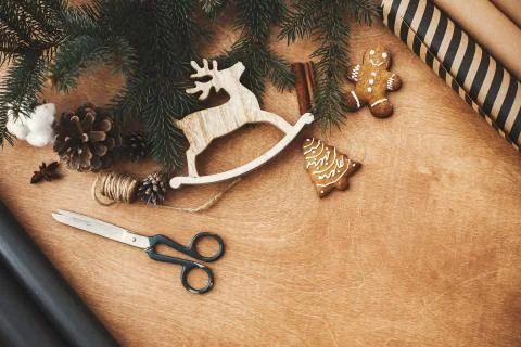 Christmas rustic flat lay. Stylish wrapping paper, wooden reindeer, gingerbre Stock Photos