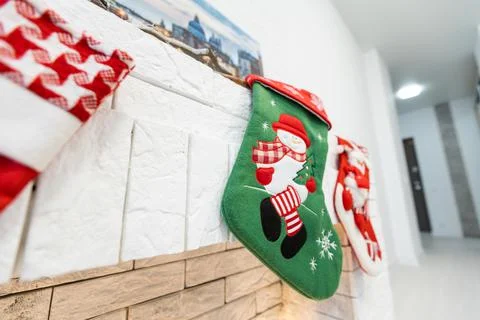Christmas socks for Santa Claus gifts hang over the fireplace in the house. Stock Photos