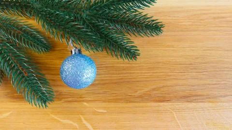 Christmas spruce branch and blue toy ball on a natural wooden background with Stock Photos