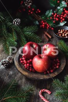 Christmas still life. Red delicious apples, cranberries, nuts, pine cones and Stock Photos