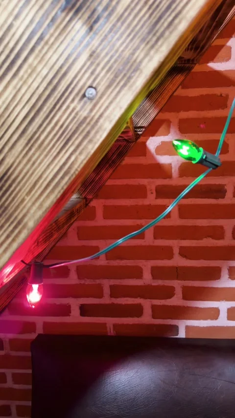 Christmas string lights decorating rustic wood beam and brick wall in cozy cabin Stock Footage 341459986