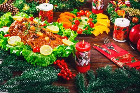 Christmas table dinner time with roasted meats, candles and New Year decor. B Stock Photos