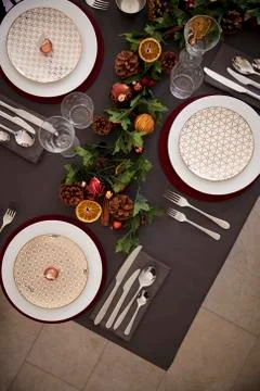 Christmas table setting with baubles arranged on plates and green and red tab Fotos de archivo