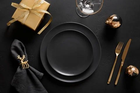 Christmas table setting with black plate and golden decorations on black ba.. Stock Photos