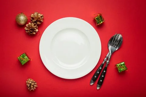 Christmas table setting decorated with empty plate, golden pine cones, and gift Stock Photos