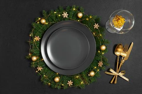 Christmas table setting with empty black plate, golden cutlery and a glass on Stock Photos