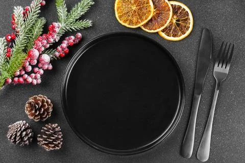 Christmas table setting with empty black plate, silver cutlery and holiday .. Stock Photos