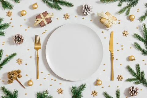 Christmas table setting with empty plate, fir branches and golden festive dec Stock Photos