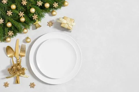 Christmas table setting with empty white plate and gold decor on a white Stock Photos