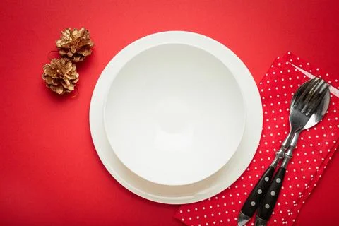Christmas table setting with empty white plate and golden pine cones Stock Photos