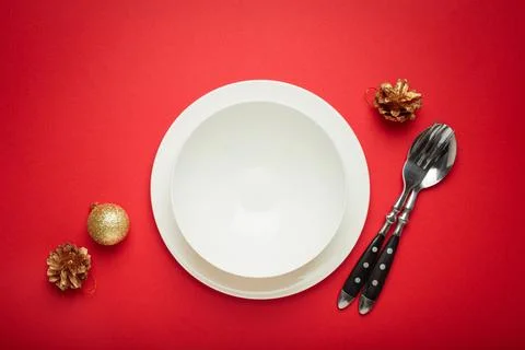 Christmas table setting with empty white plate, fir branch and golden pine cones Foto stock