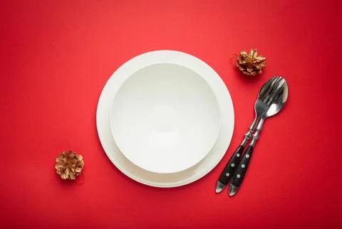 Christmas table setting with empty white plate, fir branch and golden pine cones Foto stock