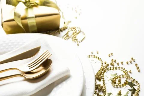 Christmas table setting with golden decor and light on white. Stock Photos