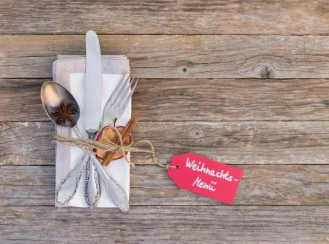 Christmas table setting with menu tag, cutlery and napkin on wood background Stock Photos