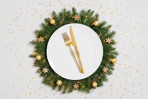 Christmas table setting with a New Year wreath, golden cutlery and confetti o Stock Photos