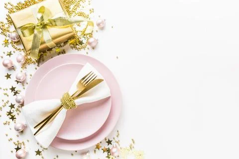 Christmas table setting with pink dishware, golden silverware on white back.. Stock-Fotos