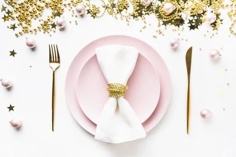 Christmas table setting with pink dishware, golden silverware on white back.. Stock-Fotos