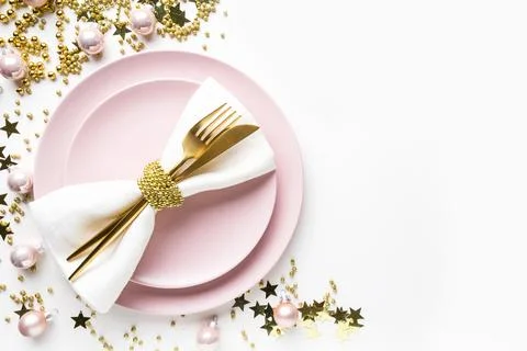 Christmas table setting with pink dishware, golden silverware on white back.. Stock-Fotos