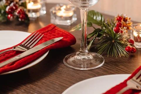 Christmas table setting. Plate and cutlery on red napkin. Candles burning o.. Stock Photos