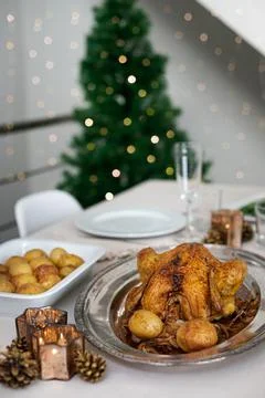 Christmas table setting with roasted chicken and christmas tree on background. Stock Photos