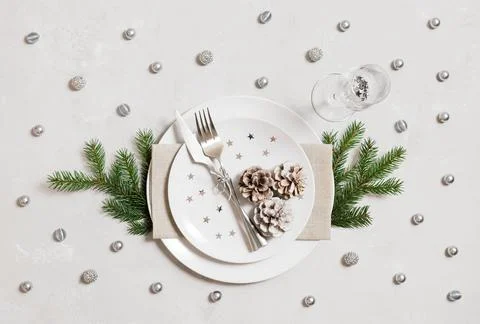 Christmas table setting with silver decorations on a gray background. Top vie Stock Photos