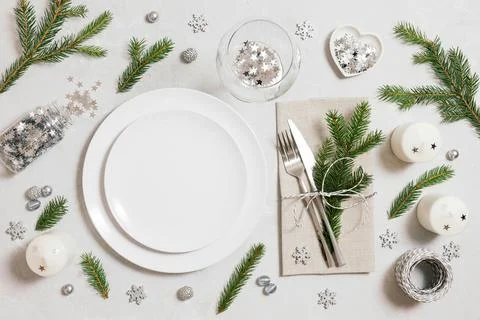 Christmas table setting with silver decorations and fir branches on a gray ba Stock Photos