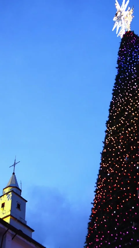 Christmas tree against a deep blue evening sky, while a church spire adds s.. 動画素材 339743549