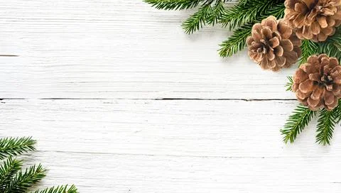 Christmas tree branches and pine cones on white wood background Stock Photos