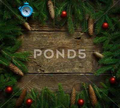 Christmas tree branches with cones and christmas decorations on wooden textur Stock Photos
