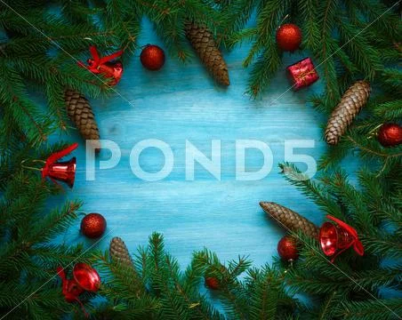 Christmas tree branches with cones and christmas decorations on blue wooden t Stock Photos