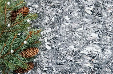 Christmas tree branches with cones in silver tinsel. Christmas background. Stock Photos