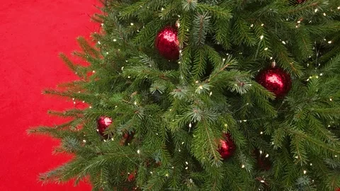Christmas tree with dark red balls and flashing garland on a red background Stock Footage 323510087